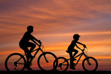 silhouettes of two cyclists against the background of the sunset