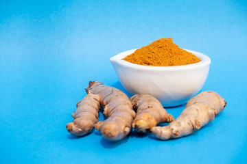 turmeric fresh and turmeric powder on blue background. concept healthy spice diet