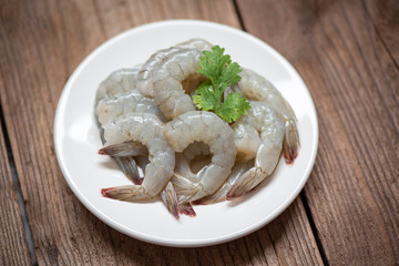 raw shrimp on white plate and wooden background for cooking / close up fresh shrimps or prawns Seafood shelfish
