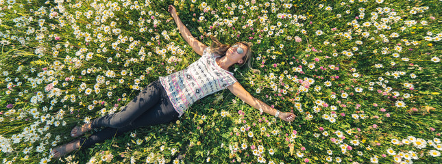 Young beautiful woman relaxing in the field with flowers. Overhead aerial view. Banner edition.