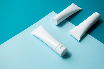 Moisturizer hand cream white plastic tubes mockup on blue trandy paper background, isometric. Blank skin care beauty product packaging