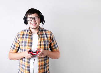 Smiling young man playing video games holding a joystick isolated on gray background