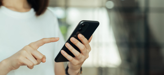 Closeup of young woman hand holding smartphone and chatting with friends at social network.