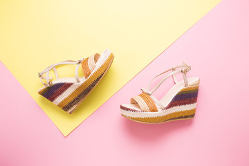 Female summer sandals on a yellow-pink background close-up.