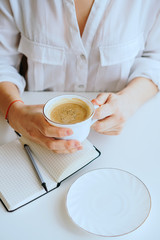 girl makes notes in a notebook, next is a coffee mug