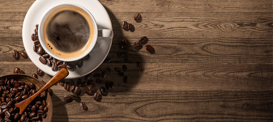 Cup of coffee and coffee beans on wooden background