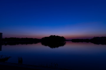 Obraz premium island on lake landscape silhouette idyllic long exposure landscape scenic view in purple dark blue colorful of twilight lighting after sunset