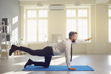 Businessman doing yoga exercises while lying in the office.