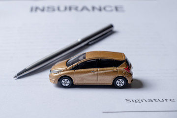 Car and pen on insurance documents. Car insurance concept