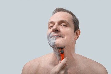 middle aged man shaves with a razor. Portrait Of Handsome Man Shaving His Face
