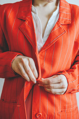 girl buttons a red jacket on a button