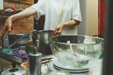 Obraz na płótnie Canvas Unrecognizable woman washes dishes in kitchen