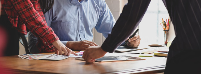 Graphic designer team consulting on their project with digital tablet and colour swatch