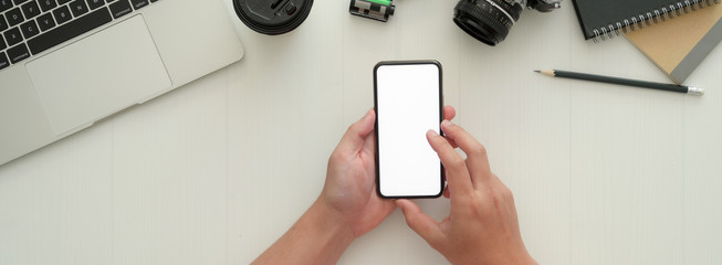 Overhead shot of photographer using mock-up smartphone on white worktable
