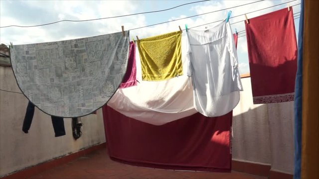Ropa tendida en el terrado de un edificio de viviendas: camisetas, s&aacute;banas, manteles y toallas. D&iacute;a soleado.
