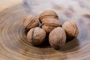 Walnuts close-up on a table from a cut of a poplar trunk, growth rings. Burnt wood texture.