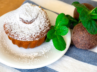 chocolate muffin with icing sugar on a white plate and cocoa