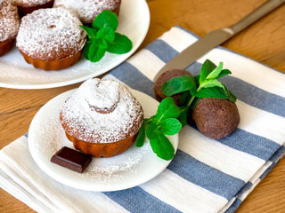 chocolate muffin with icing sugar on a white plate and cocoa