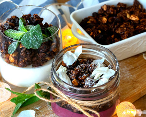 two desserts in a glass. Berry-curd dessert with granola. On a wooden board with garland 