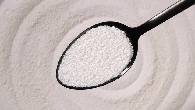 collagen powder in black spoon and collagen powder background rotating. Natural beauty and health supplement top view