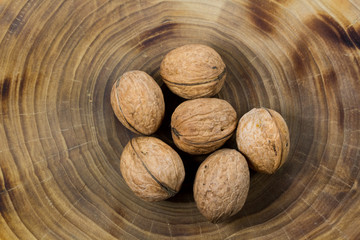 Walnuts close-up on a table from a cut of a poplar trunk, growth rings. Burnt wood texture.