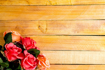 Handmade roses lie on a wooden background. Background layout with free text space.