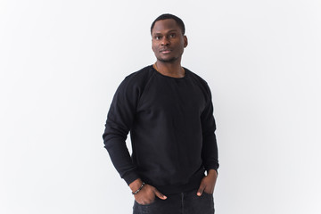 Portrait handsome young black man dressed in jeans and sweatshirt on white background. Street fashion and modern youth culture.
