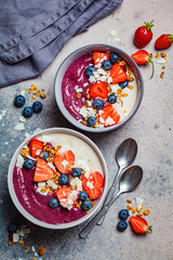 Berry smoothie bowl with granola, berries and coconut, gray background, top view. Healthy vegan food concept.
