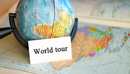 World tour - text on a white sheet in little Globe on the background of the atlas map