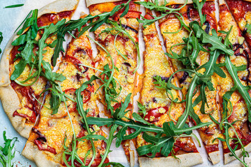 Vegan homemade pizza with tomato sauce, pepper, vegan cheese and arugula, top view.  Healthy vegan food concept.