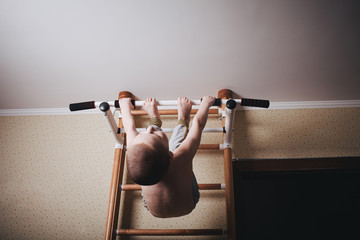 Home workout. The boy hangs head down on the horizontal bar.