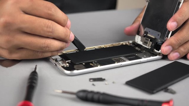 Locked down and close up of technician or engineer repairing or replace new parts of broken and damaged smartphone on desk. 4K resolution ultra HD