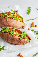 Baked sweet potato stuffed with fried chickpeas and vegan cheese on white background. Healthy vegetarian food concept.