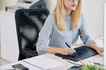 Female graphic designer working on tablet and drawing with stylus