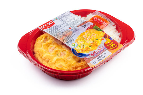 CHONBURI, THAILAND-MAY 15, 2020 : Shrimp omelette with rice in plastic box food package and chilli sauce in sachet. Microwave food for to go. Ready meals. Food packaging with easy peel plastic film.