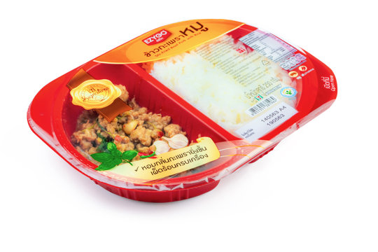 CHONBURI, THAILAND-MAY 15, 2020 : Stir-fried basil pork with rice in red plastic box food package. Microwave food for to go. Ready meals. Food packaging with easy peel plastic film. Thai food.
