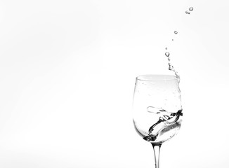 Water in a wine glass. Splash of liquid on a white background. Isolated object. Spray. Copy space for text. Selective focus.