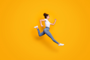 Full length profile photo of crazy lady jumping high up running fast final line fit cross competitions marathon wear white t-shirt jeans isolated yellow bright color background