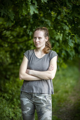 Portrait of a beautiful woman with long hair on a green background. The girl is wearing a gray short-sleeved T-shirt and army pants.