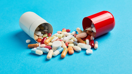 Bunte Medikamente in großer Kapsel auf blau