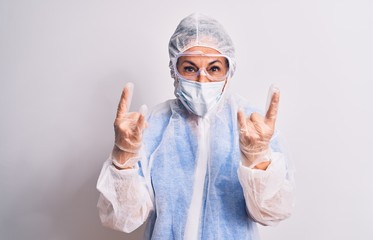 Middle age nurse woman wearing protection coronavirus equipment over white background shouting with crazy expression doing rock symbol with hands up. Music star. Heavy concept.