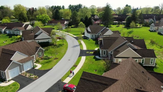 Retirement Community, Independent Living For Senior Citizens, Happy Husband And Wife Walk Hand In Hand Through Neighborhood Of Homes