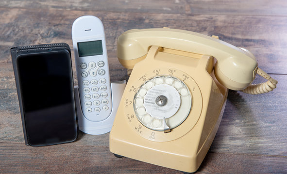 retro phone and new cell phone on wooden board