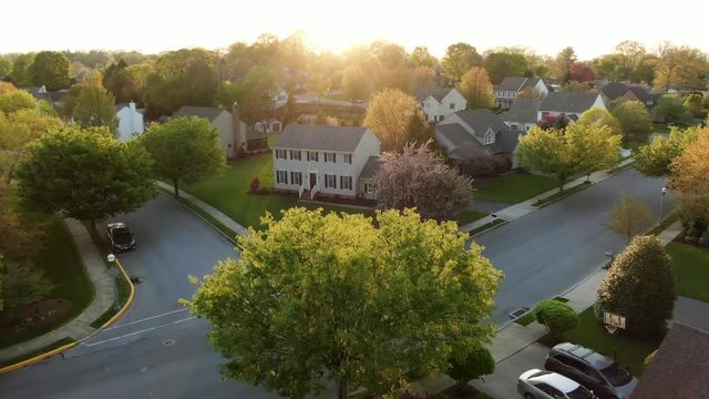 Dramatic light, aerial turn reveals American neighborhood, residential development community during spring season magic hour, Small Town America