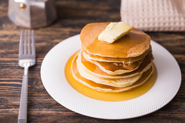 Small pancakes with maple syrup and butter on wooden table. Breakfast concept.