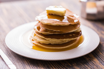 Small pancakes with maple syrup and butter on wooden table. Breakfast concept.