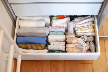 Vertical storage of clothing. Clothing folded for vertical storage in the linen drawer. Nursery. Sliding wardrobe. Room interior. Neatly folded clothes in chest of drawers. Newborn baby clothes. 