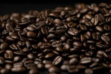 Pile of roasted coffee beans splash on the black floor
