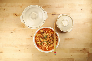 Malaysian curry yellow mee noodle with roasted chicken slice in white bowl on wooden background