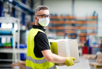 Man worker with protective mask working in industrial factory or warehouse.